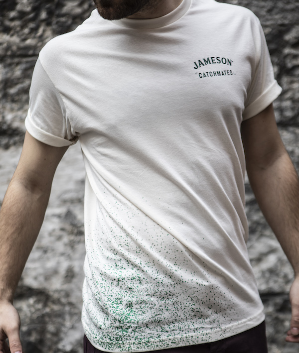 A white t-shirt with green glitter splashed across it, and a Jameson Catchmates logo on the chest.
